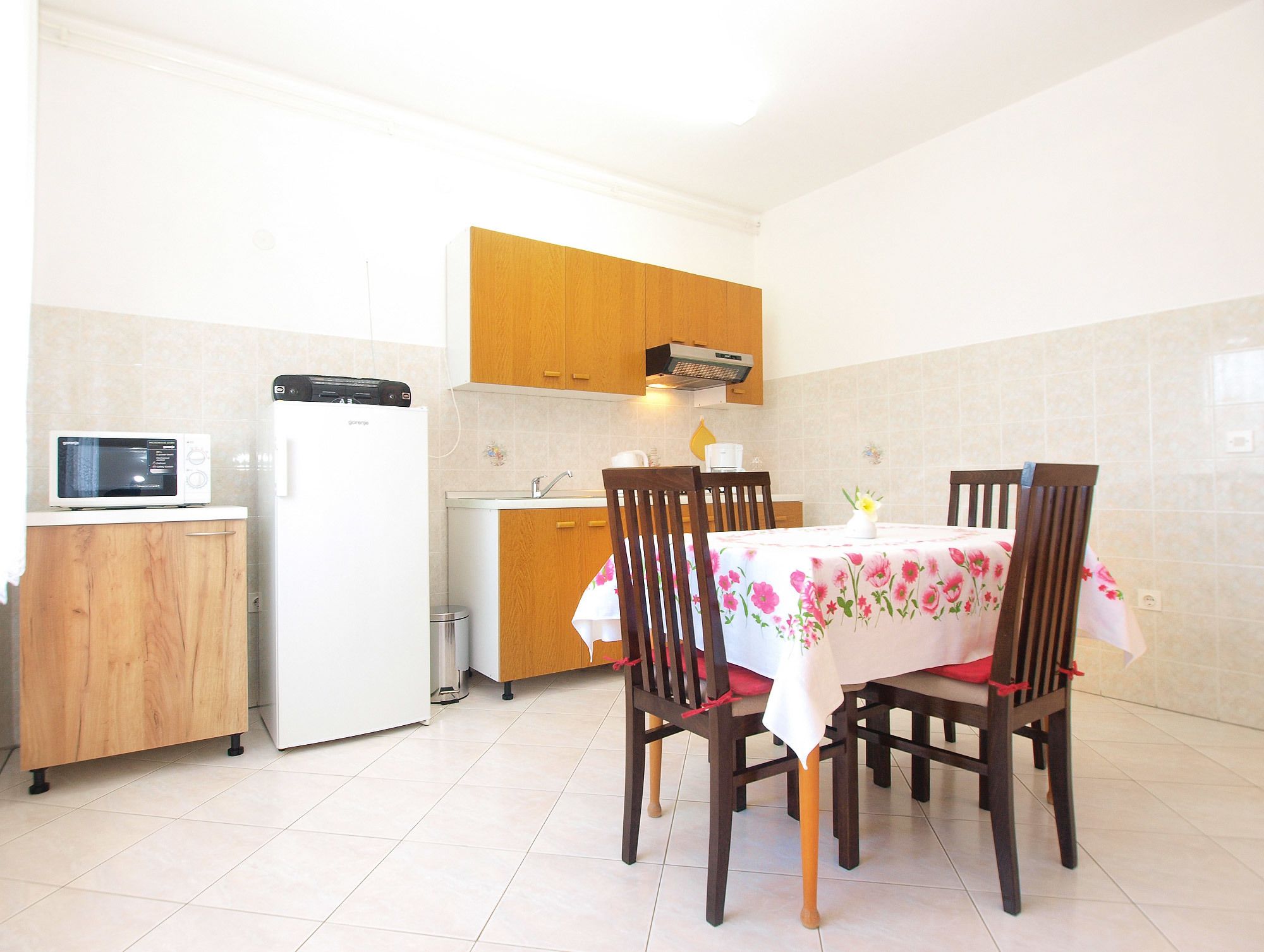 A compact kitchen with a microwave, refrigerator, and wooden cabinets.
