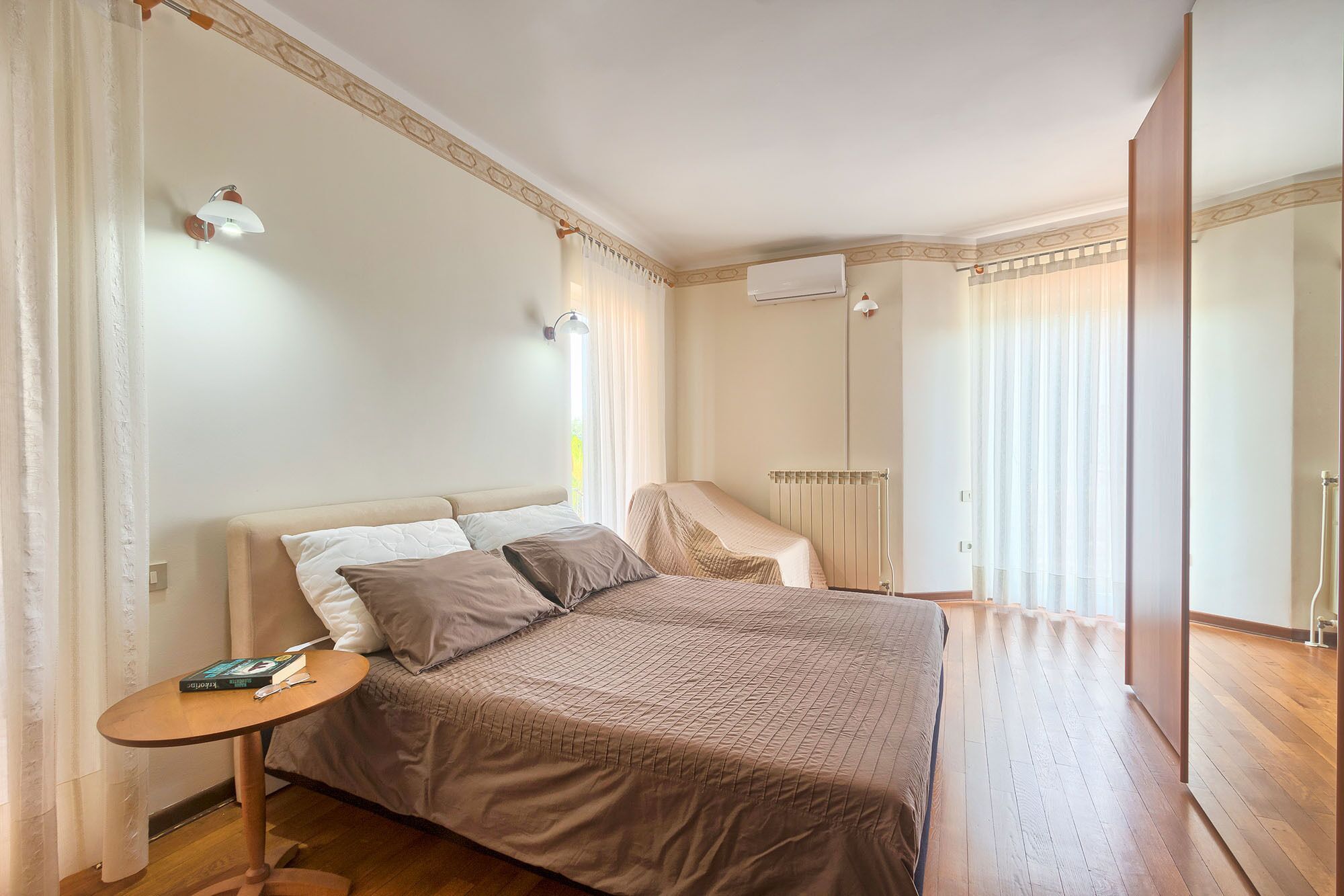 A bedroom with a large bed, a bedside table, a radiator, and a wardrobe.