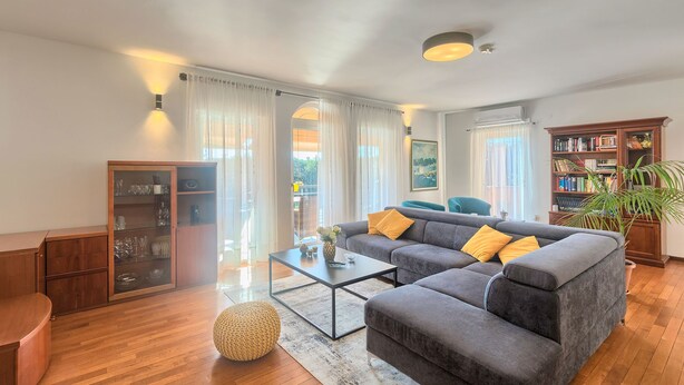 Una sala moderna con un sofá gris, una mesa de centro y una estantería.