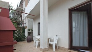 A patio area with a table and chairs, a large window, and a red structure. - Apartment 1569 (Pula)