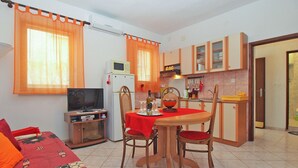 A compact living space with a dining area, kitchenette, and a TV. - Apartment 1569 (Pula)