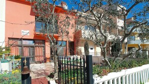 Un patio con un sendero rojo, una cerca blanca y un edificio de fachada roja.