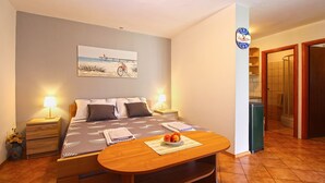 A bedroom with a bed, bedside tables, a painting, a clock, and a table with fruit. - Apartment 1573 (Fazana)