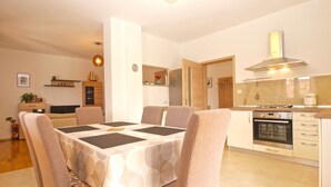 A modern kitchen with a dining area, featuring a table with chairs, a built-in oven, and a stove. - Apartment 1573 (Fazana)
