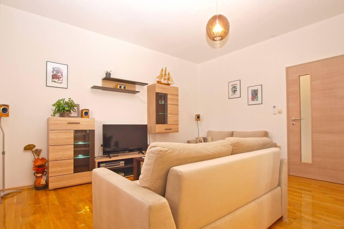 A modern living room with a sofa, TV, wooden cabinet, and decorative items.