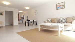 A modern living room with a white sofa, a coffee table, and a dining area with a white table and chairs. - House 1581 (Pula)