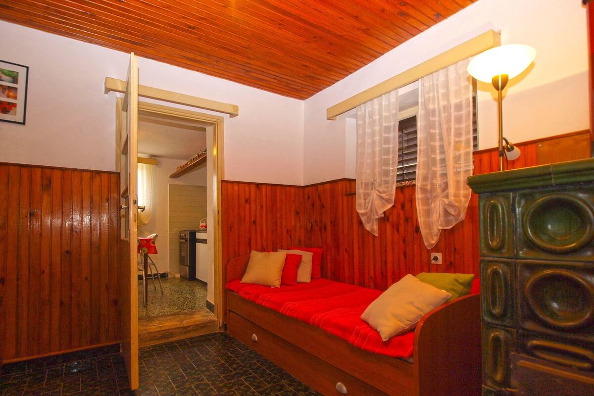 A room with a wooden bed, a dresser, a lamp, and a door leading to another room.