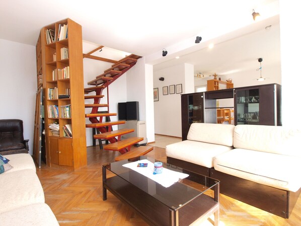 Relax in this stylish living room with a unique staircase bookshelf, comfortable sofa, and sleek coffee table.