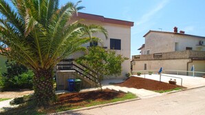 A residential area with a palm tree, a staircase, and a building with a red roof. - Apartment 1583 (Medulin)