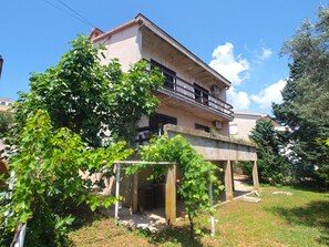 Two-story building with a balcony and a garden below.