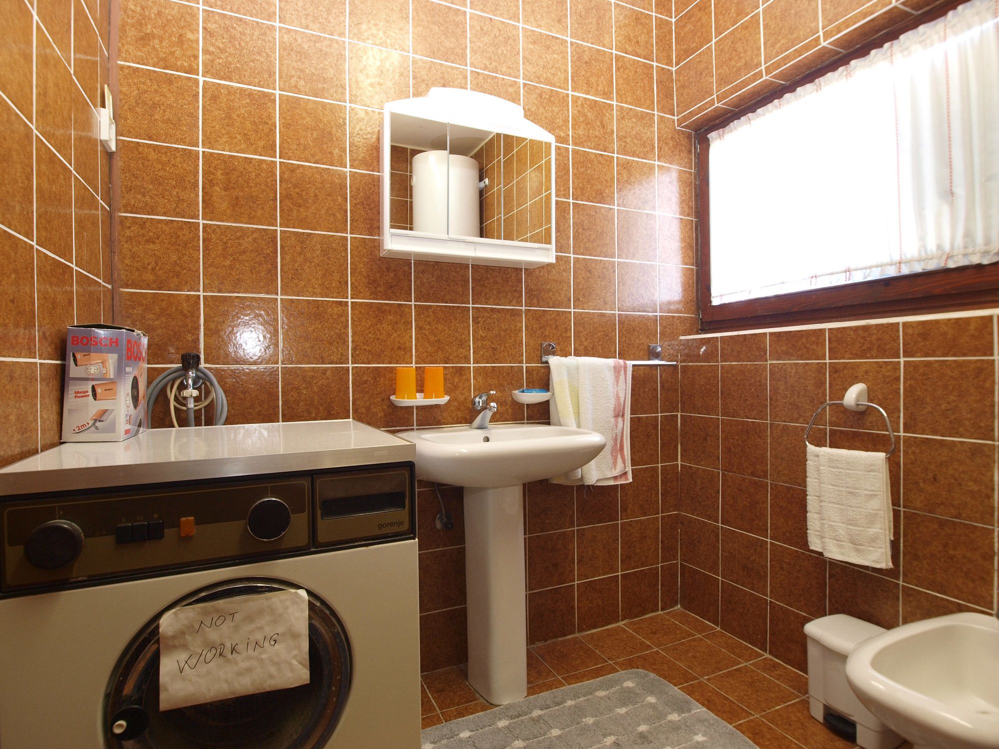 Un baño pequeño con lavadora, lavamanos y bidé.