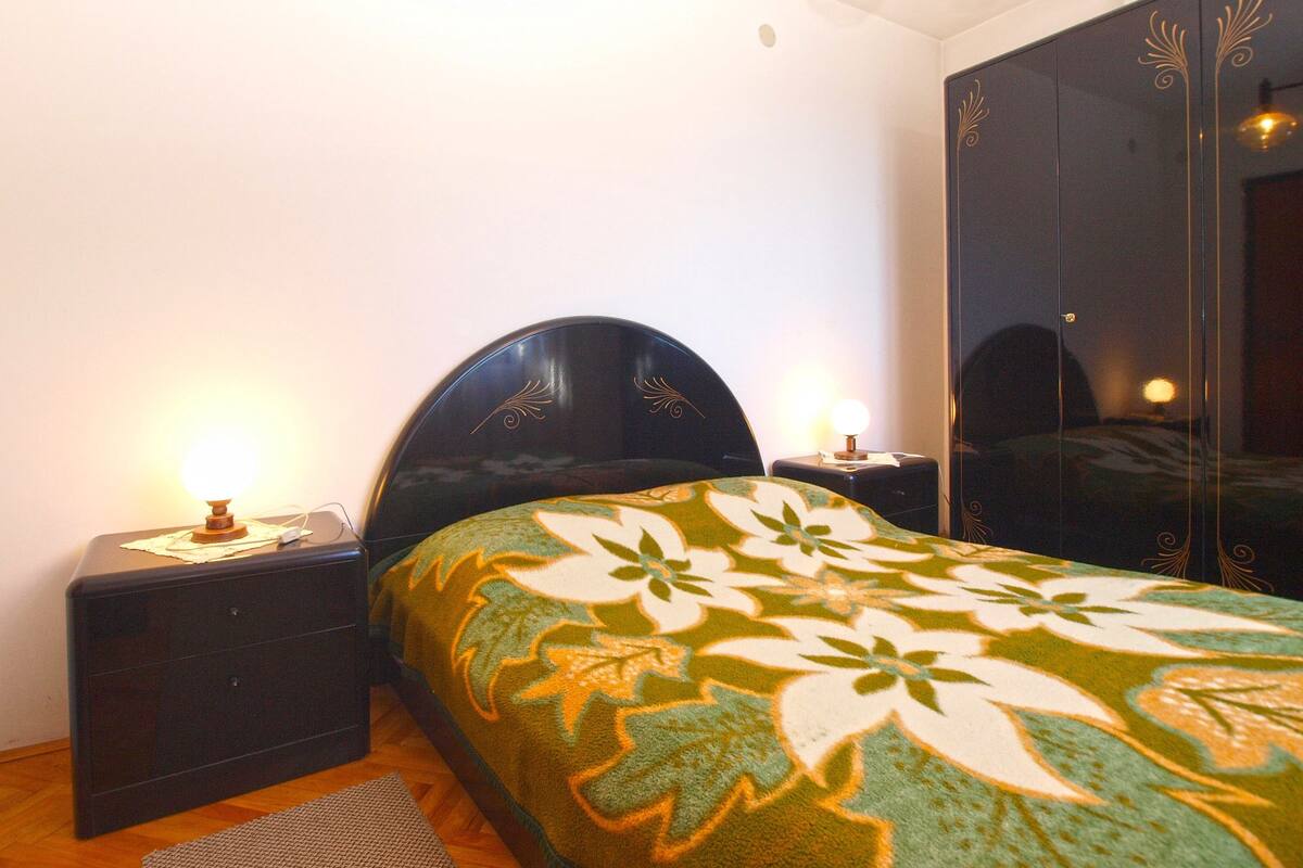 A bedroom with a bed, nightstands, a wardrobe, and a chandelier.