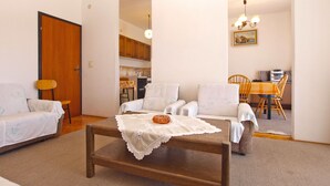 Un salon comprenant un canapé, des fauteuils, une table basse et un coin repas avec une table et des chaises.