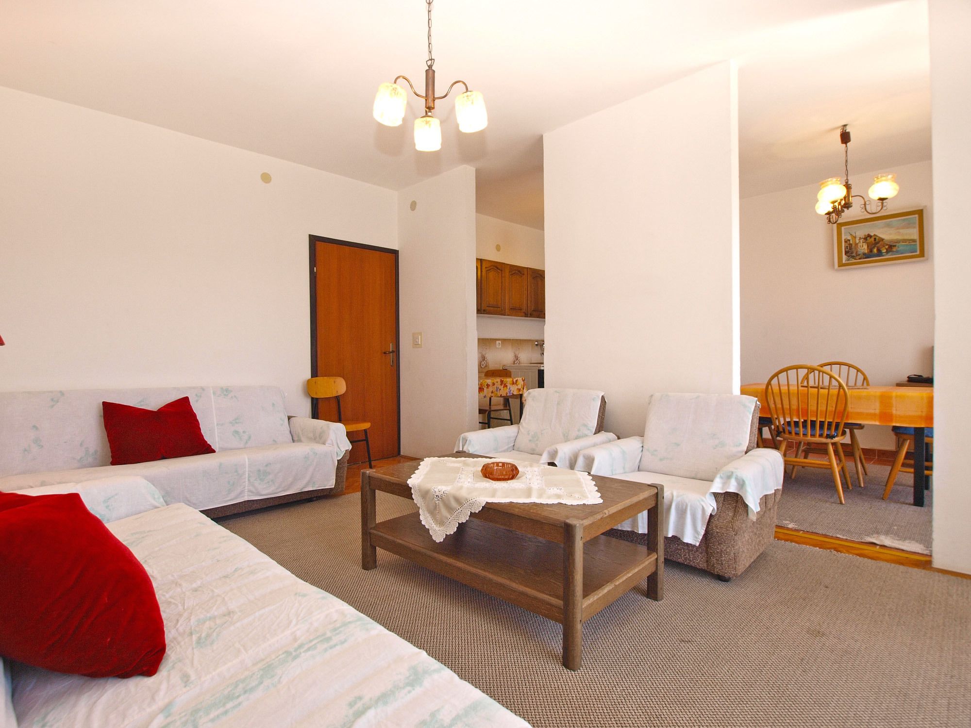 A living room with a sofa, armchairs, a coffee table, and a dining table with chairs.