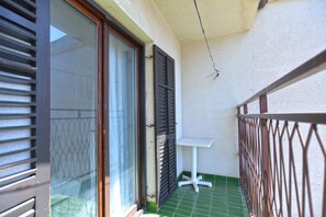 A balcony with a white table, metal railing, and a green tiled floor. - Apartment 1586 (Pula)