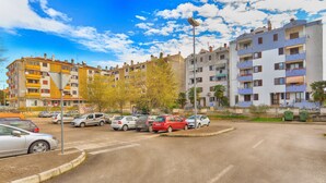 Um estacionamento com vários carros, rodeado por edifícios residenciais altos com varandas e antenas parabólicas.