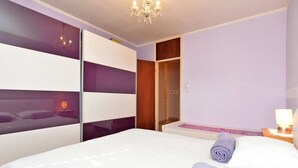 Quarto moderno com uma cama grande, guarda-roupa, closet e um candelabro.