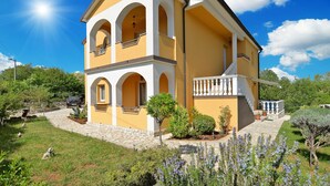 A two-story building with a yellow facade, arched windows, and a balcony with white balustrades.