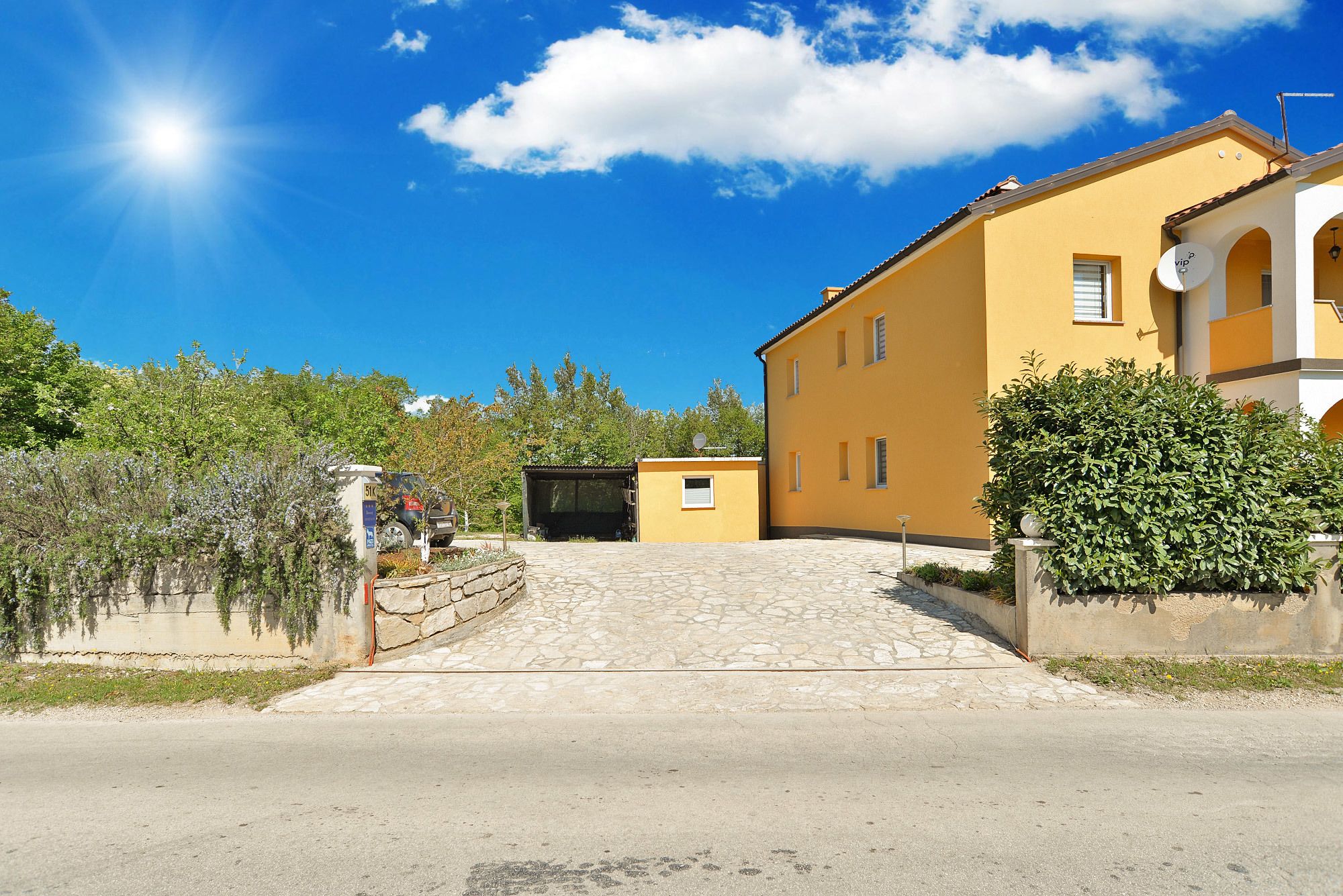 A yellow building with a stone staircase leading to a covered entrance.