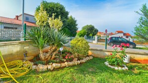 Un jardín con diversas plantas y una señal de stop al fondo.