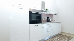 Una cocina moderna con armarios blancos, un horno Bosch y una cafetera.