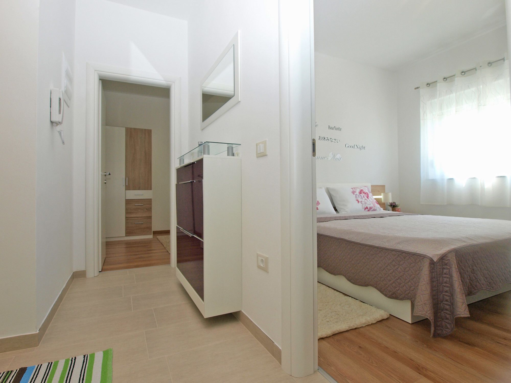 Une chambre à coucher avec un lit, une armoire, un miroir et une table de chevet.