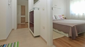 Un dormitorio con cama, armario, espejo y mesita de noche.