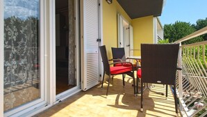 An outdoor patio with a table and chairs, a sliding glass door, and a yellow wall. - Apartment 1623 (Fazana)