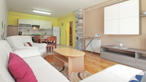 A modern living room with a sofa, coffee table, and a dining area with chairs. - Apartment 1623 (Fazana)