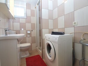 Une salle de bain moderne équipée de toilettes, d’un lavabo et d’un lave-linge.