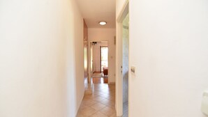 A narrow hallway with a tiled floor leading to a room with a door. - Apartment 1633 (Pula)