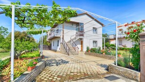A two-story house with a balcony, a staircase, and a garden with potted plants and flowers. - Apartment 1633 (Pula)