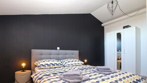 Un dormitorio con cama, dos mesitas de noche, un armario y una lámpara colgante.
