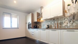 Una cocina moderna con armarios blancos, horno empotrado y salpicadero con diseño.