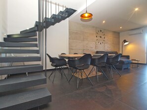 Un interior moderno con una escalera, comedor y un reloj en la pared.