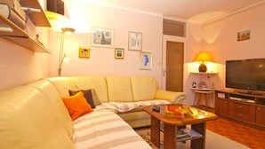 A living room with a sofa, a coffee table, a TV, and a lamp. - Apartment 1635 (Pula)
