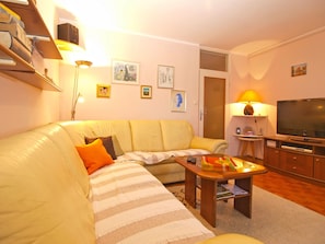 Relax in this inviting living room with a sofa, coffee table, flat-screen TV, and bookshelf.