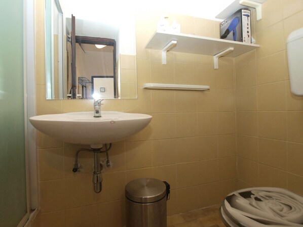 A bathroom with a sink, mirror, and shelves.