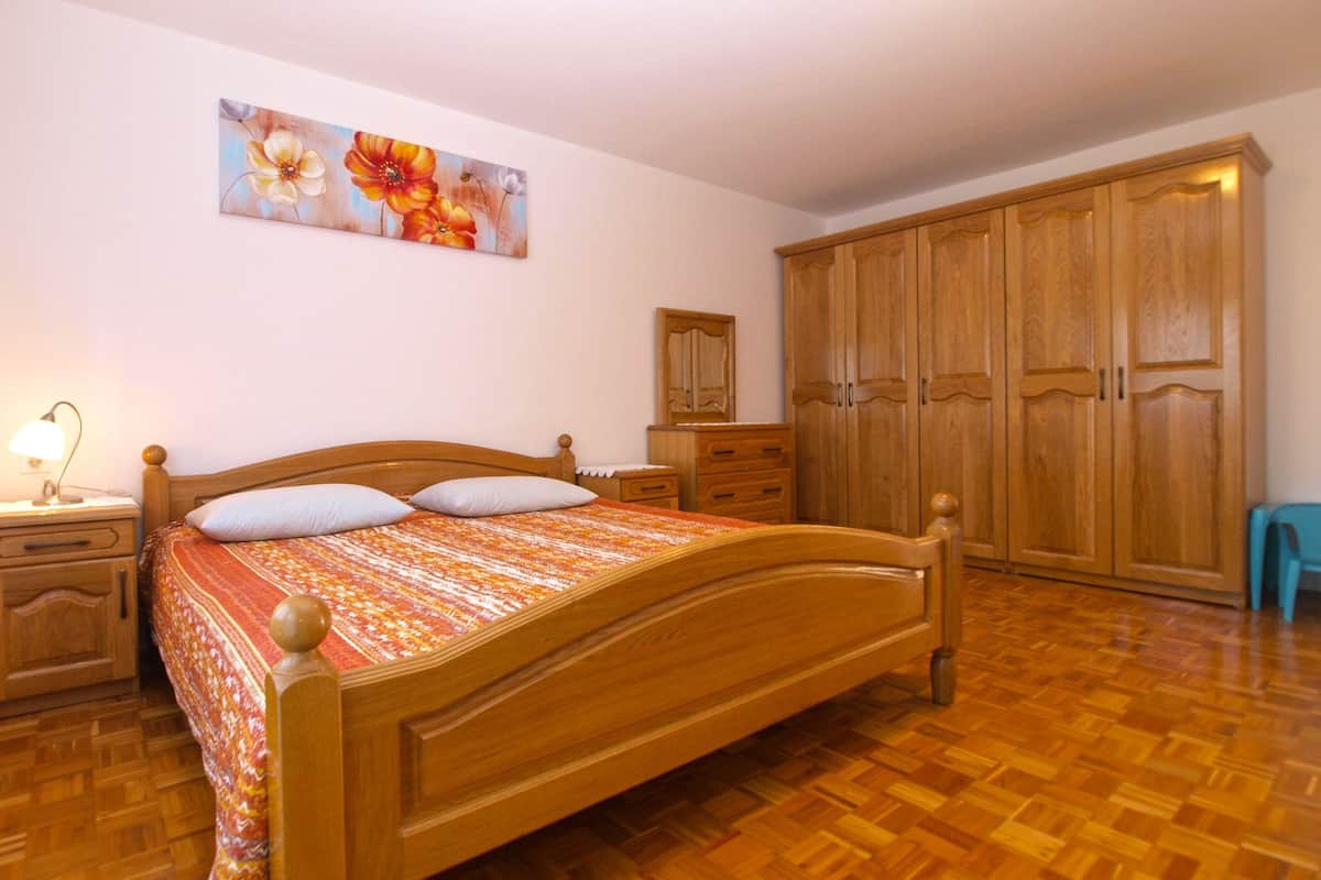 Quarto com cama de madeira, mesa de cabeceira, cômoda e guarda-roupa.