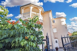 Classic two-story building with a balcony on the upper floor, featuring a black metal gate.