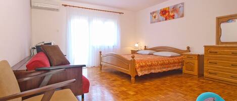 Ein Schlafzimmer mit einem hölzernen Bett, einem Sessel, einer Kommode und einem Nachttisch.
