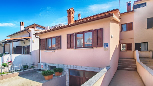 A two-story building with a tiled patio and potted plants. - Apartment 1639 (Pula)