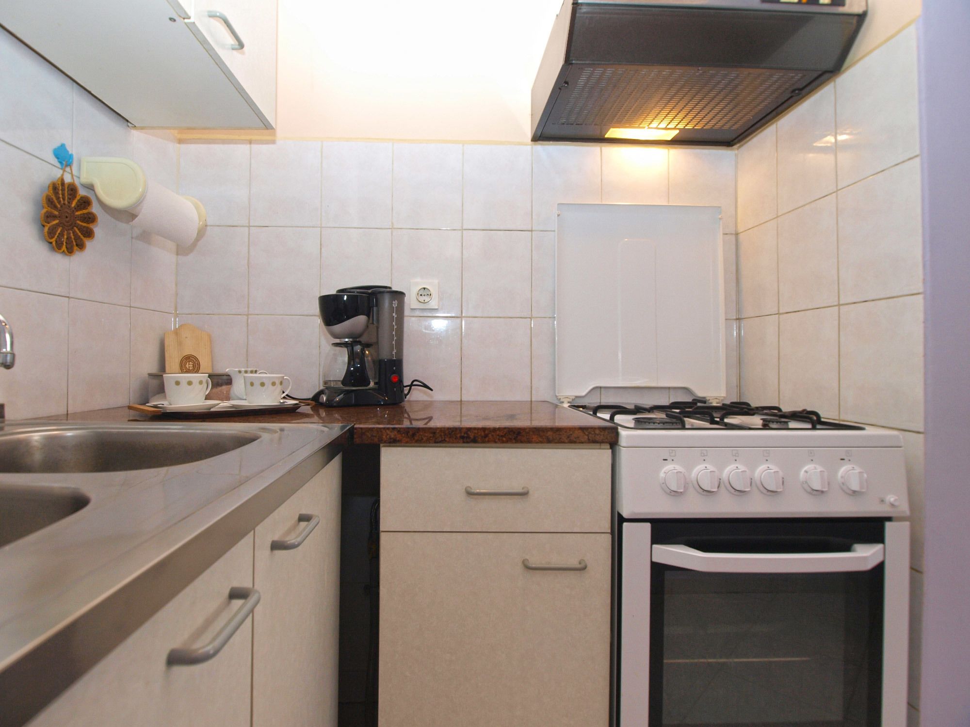 A kitchen with a gas stove, a coffee maker, a sink, and a cabinet with drawers.