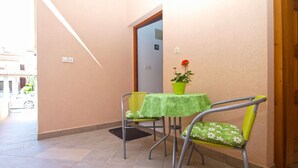 A small room with a green table and two chairs, a potted plant, and a door leading to another room. - Apartment 1639 (Pula)
