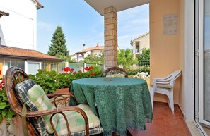 A patio with a round table covered by a green tablecloth, wicker chairs, and a white plastic chair. - Apartment 1648 (Porec)