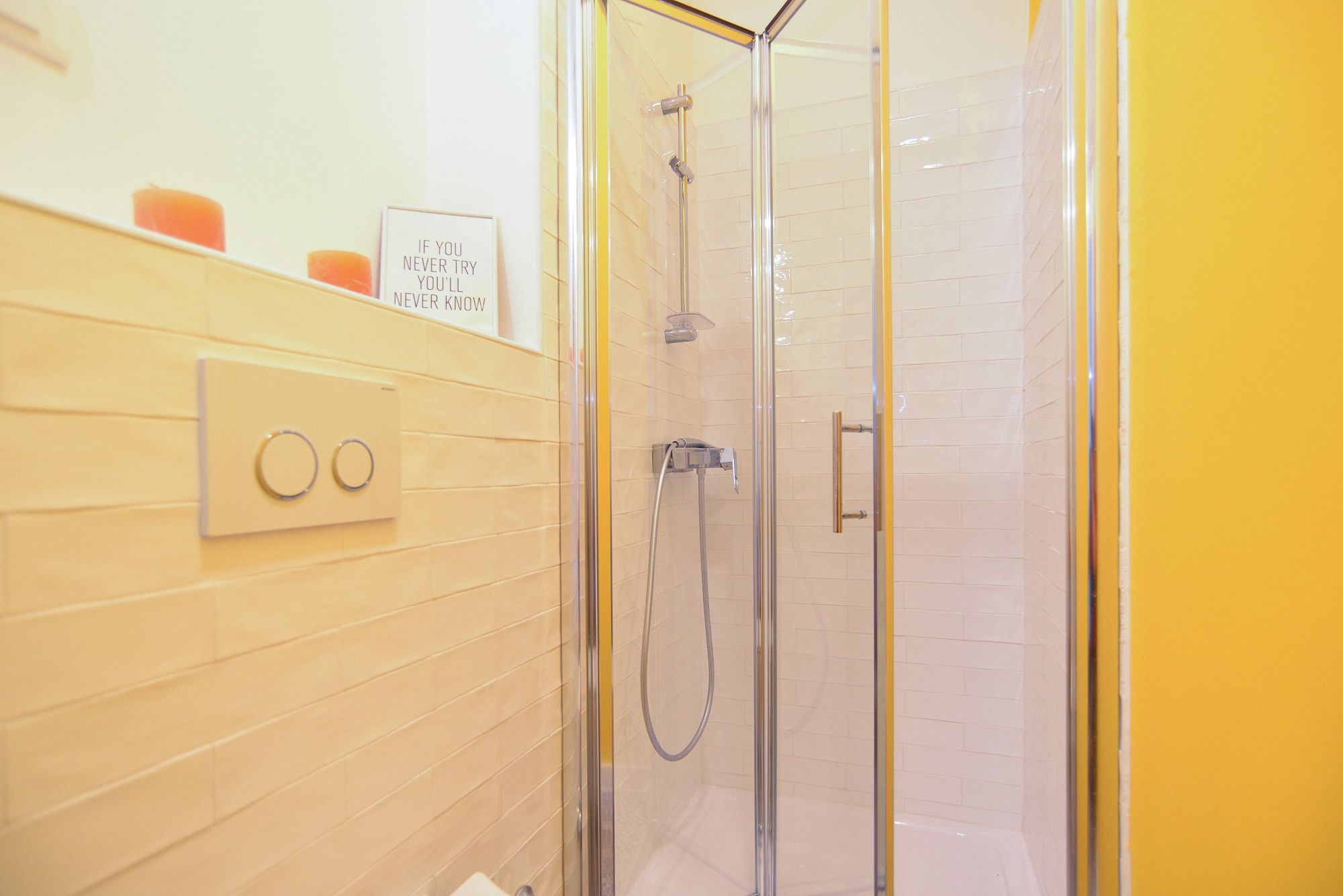 A modern bathroom with a glass-enclosed shower, a wall-mounted light switch, and a motivational quote sign.