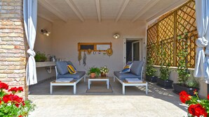 An outdoor seating area with two white sofas, a small table, and potted plants. - House 1650 (Vodnjan)