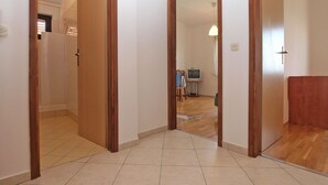 Un corridoio con porte in legno che danno su un bagno e una zona giorno.