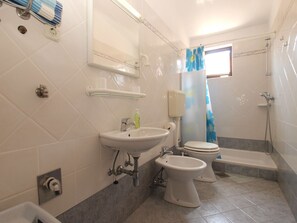 A bathroom with a sink, toilet, bidet, and shower.