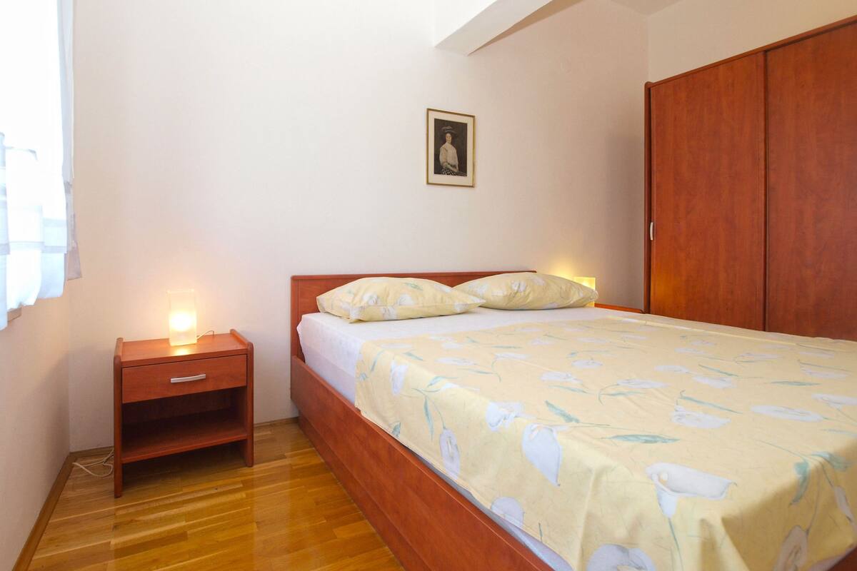 Une chambre à coucher avec un lit en bois, une table de chevet, une armoire et un tableau encadré au mur.
